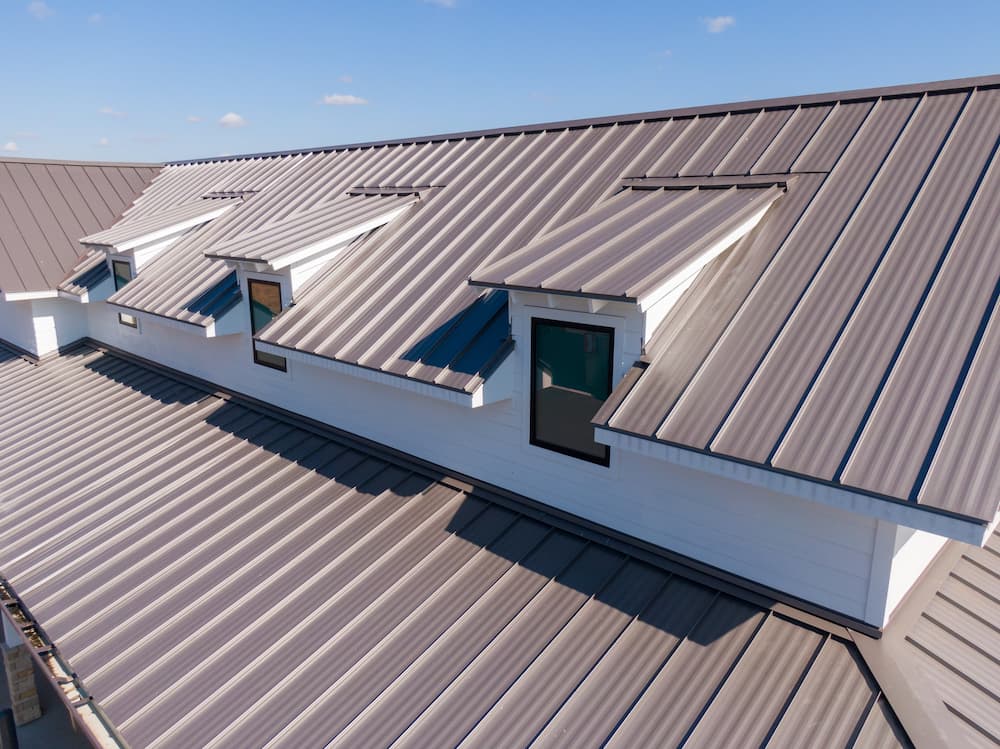 Close-up of a modern residential roof with metal roofing panels and dormer windows, highlighting the low maintenance and long-term durability of a metal roof in the Louisiana climate.