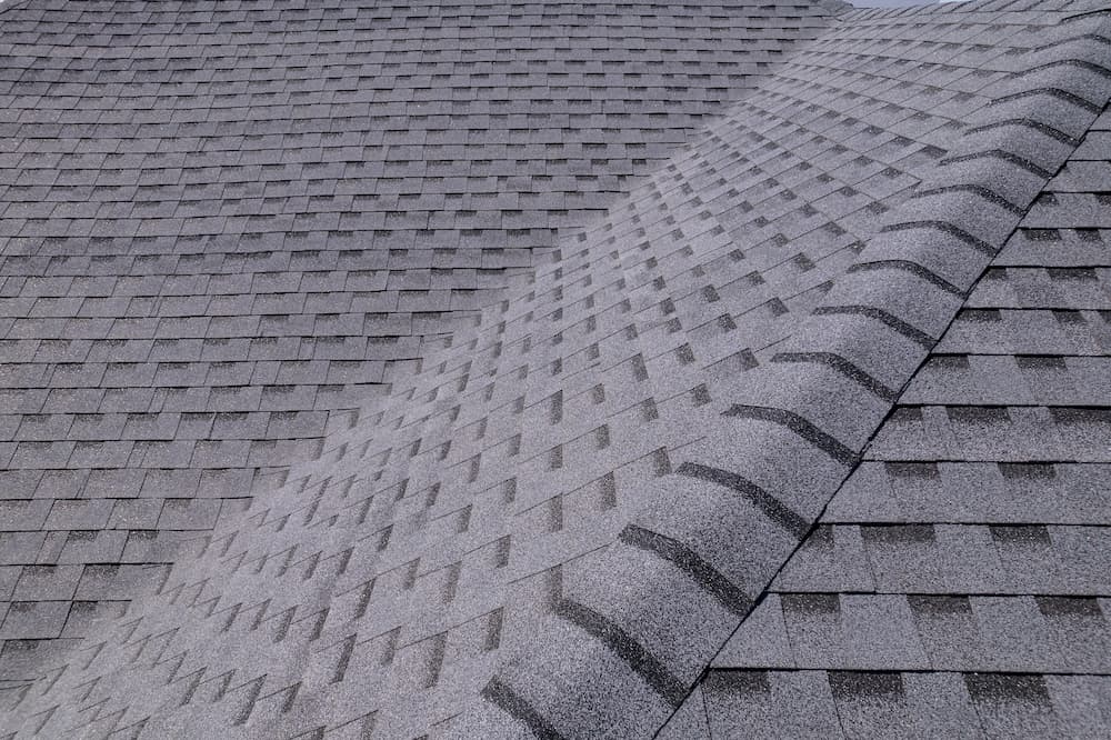 Close-up of a residential roof covered in dark gray asphalt shingles, illustrating the difference in required repair and roof maintenance when compared to a metal roof in Louisiana's climate.