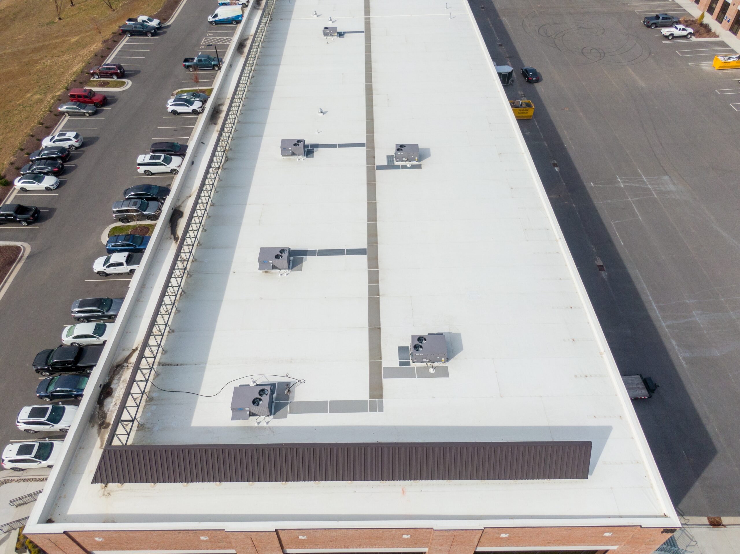 Aerial drone view of a white commercial flat roof with HVAC units, illustrating how regular maintenance can maximize commercial roofing ROI.